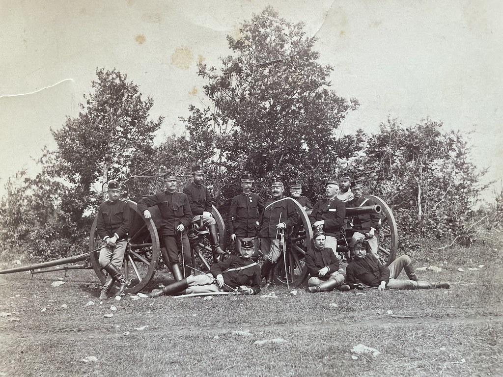 Victor Klinger, unbekannter Ort im ehemaligen Österreich-Ungarn, ca. 1880. Gruppenfotografie einiger Soldaten und Offiziere vor zwei Geschützen. Das Foto wurde vom k.u.k. Artillerie-Oberleutnant Victor Klinger gemacht und von Charles Scolik in Wien kopiert.