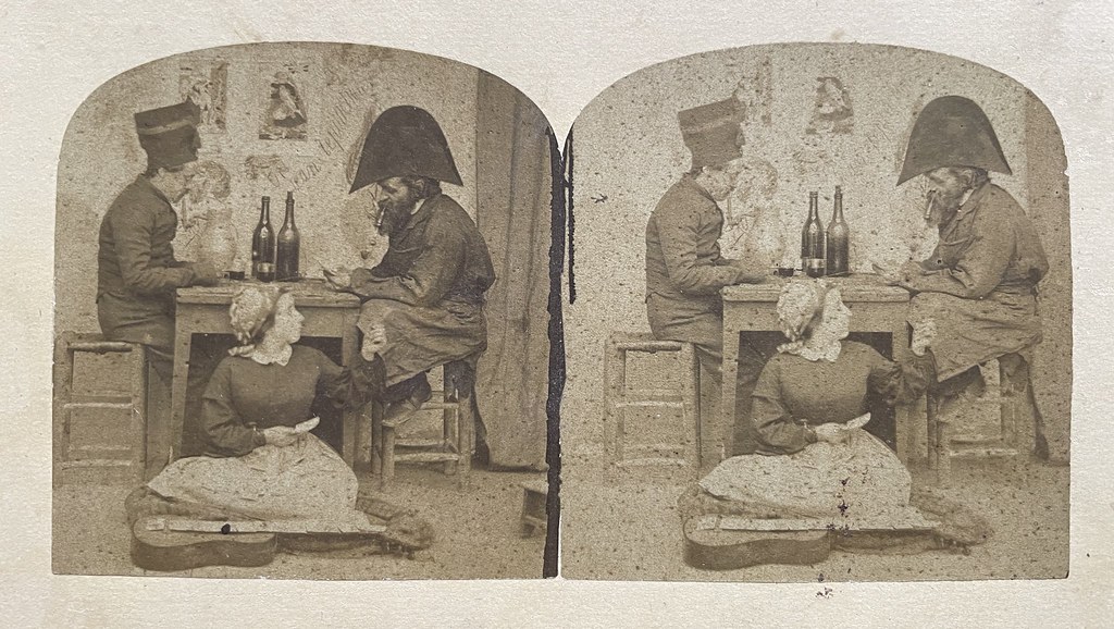 Unbekannter Fotograf, Unbekannter Ort in Frankreich (?), ca. 1860er. Zwei Männer sitzen zu Tisch und spielen Karten, während eine Frau am Boden sitzt und einem der Männer, vermutlich ihrem Mann, hilft.