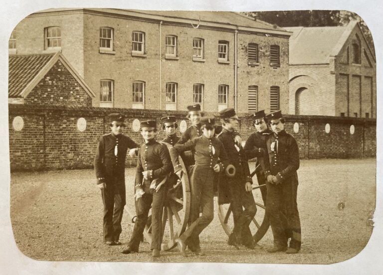 Unbekannter Fotograf, unbekannter Ort in England, ca. 1855. Eine Gruppe junger Artilleristen posieren mit einem Artilleriegeschütz vor der Kamera. Im Hintergrund sind Kasernen zu sehen.