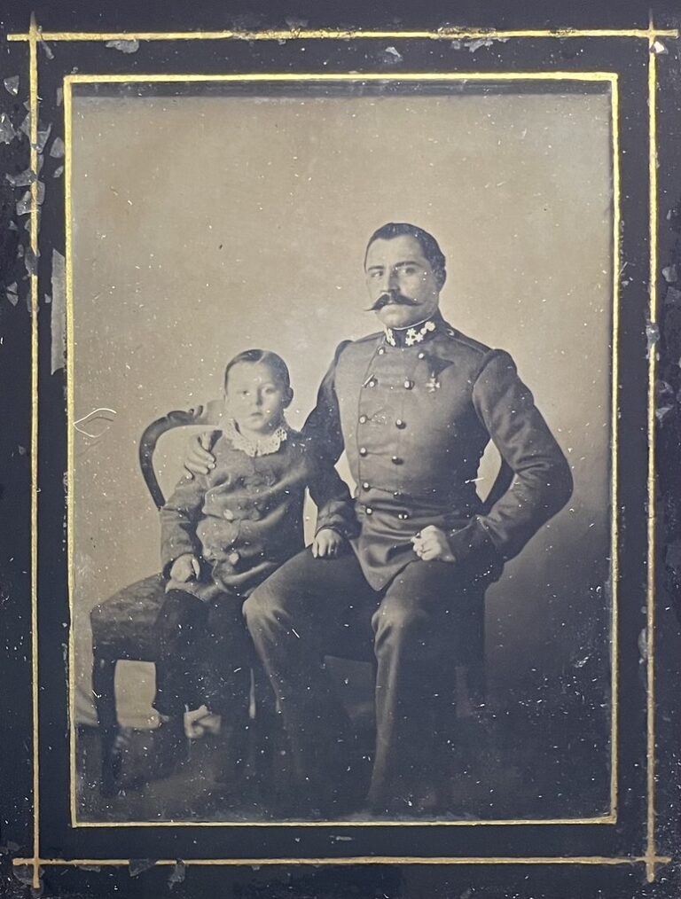 Veteran mit Kind - Ambrotypie | 1840er & 1850er, Männer, Militaria – Unbekannter Fotograf, unbekannter Ort in Österreich, ca. 1850er. Ein Veteran mit einer Medaille sitzt neben seinem Sohn auf einem Sessel.